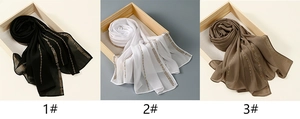 Detail of chiffon scarves in black, white, and brown with gold embroidery trim
