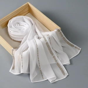 Detail of white chiffon hijab scarf with elegant gold and silver beaded stripe pattern
