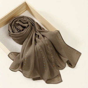 Detail of coffee brown chiffon hijab with intricate gold and silver beaded geometric trim
