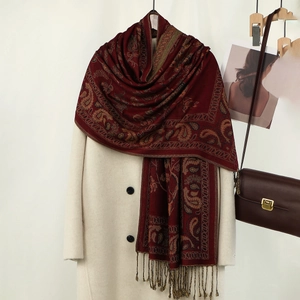 Dettaglio di sciarpa rossa con ricamo paisley e nappe annodate a mano su cappotto bianco