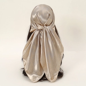 Detail eines champagnergoldenen Satinschals mit Blumenmuster und elegantem Fall
