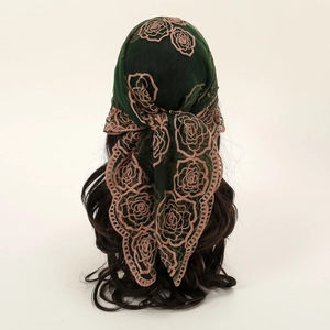 Détail du foulard vert foncé avec broderie de roses roses et bordure en dentelle