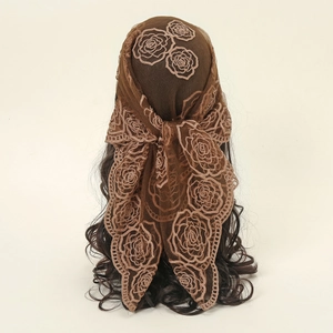 Détail d'un foulard en dentelle marron foncé avec motifs floraux de roses brodés