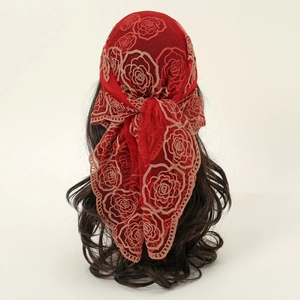 Détail d'un foulard en dentelle rouge avec broderie rose et nouage à l'arrière