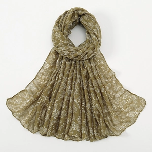 Close-up of olive green scarf featuring delicate white floral patterns and textured fabric