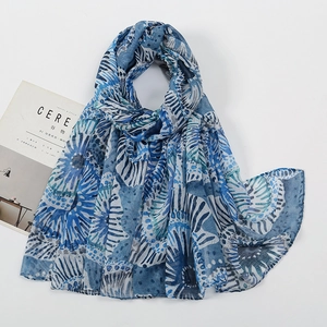 Detail of blue floral print voile scarf draped elegantly beside a lifestyle magazine