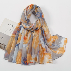 Detail of soft voile scarf featuring large vibrant orange floral prints and smooth texture