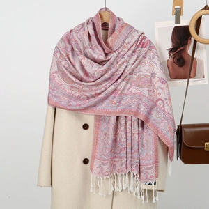 Detail of paisley print scarf with soft tassels draped over a beige wool coat
