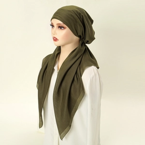 Detailed draping of olive green ethnic turban headwrap on a studio mannequin bust