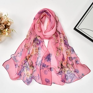 Flat lay of pink chiffon scarf with floral pattern beside dried flowers decoration