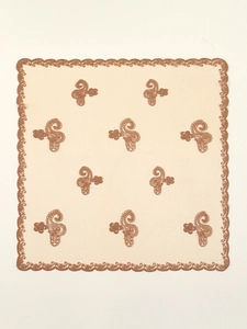 Close-up of beige square scarf with paisley embroidery and scalloped lace edges