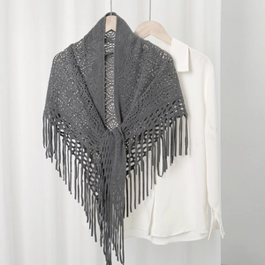 Nahaufnahme von dunkelgrauem Strickschal mit Lochmuster, langen Fransen und weicher Textur