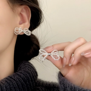 Elegant beaded bow stud earrings featuring minimalist silver beads shown on model ear