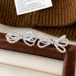 Handcrafted clear beaded bow earrings with silver bead detail on brown velvet display