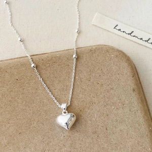 Elegant 3D heart pendant necklace with silver bead chain on a minimalist aesthetic background