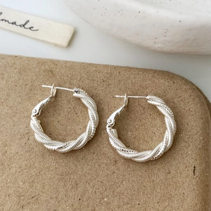 Vue détaillée de boucles d'oreilles créoles torsadées en argent avec poinçon S925
