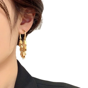 Détail de boucles d'oreilles dorées avec disques superposés portées par un mannequin