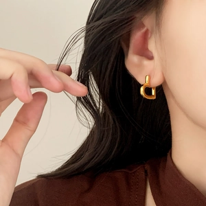 Minimalist gold heart-shaped hoop earrings worn by a model for a chic, stylish look