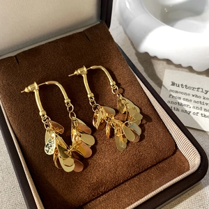 Détail de boucles d'oreilles dorées à pampilles circulaires dans un coffret à bijoux