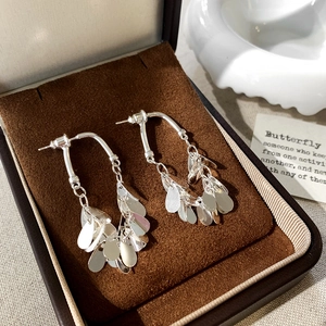 Vue macro de boucles d'oreilles argentées à pampilles avec paillettes en forme de goutte