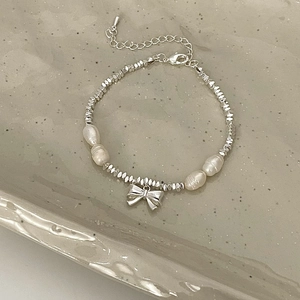 Elegant beaded silver bracelet with freshwater pearls and a central metal bow pendant