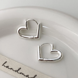 Detailed view of silver heart hoop earrings placed on a white ceramic plate