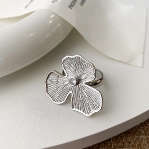 Close-up of silver flower open ring featuring textured petals and a sparkling zircon