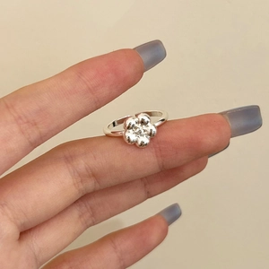 Detail shot of a silver floral ring with a zircon center worn on a finger