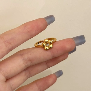 Detail of gold flower ring with cubic zirconia center and brushed texture finish