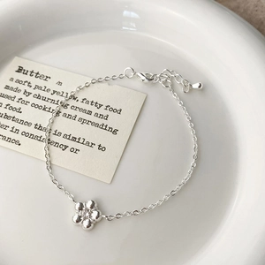 Detail view of silver floral pendant bracelet with crystal center on a ceramic plate