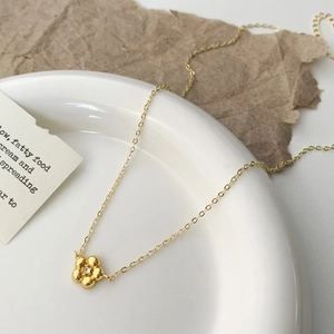 Gros plan d'un collier à pendentif fleur doré orné d'une pierre précieuse brillante