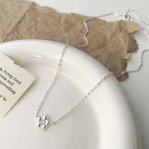 Detail of silver flower necklace pendant with zircon on a white ceramic plate