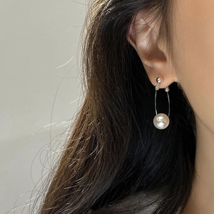 Elegant silver loop earrings with a round white pearl on a female model
