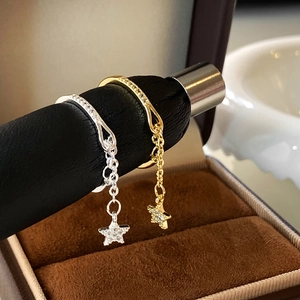 Close-up of gold and silver chain rings with dangling cubic zirconia star charms