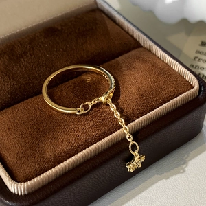 Macro shot of gold ring with a dangling star charm and chain detail on velvet