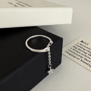 Detail of silver minimalist ring with sparkling zircon star pendant on a black textured box