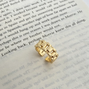 Detailed view of wide chain-link gold ring resting on a book with polished metal texture