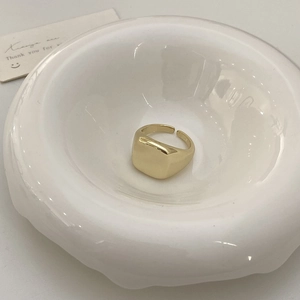 Detailed view of adjustable golden square signet ring with polished mirror finish on white tray
