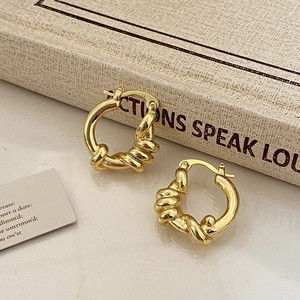 Detail of elegant gold twisted hoop earrings placed on a vintage book for a luxury look