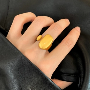 Anello aperto in oro opaco con elementi ovali minimalisti indossato su sfondo di pelle nera