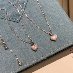 Elegant silver O-chain necklace featuring a pink heart shell pendant on denim background