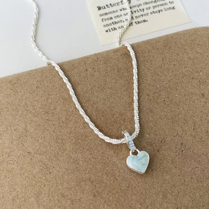 Détail du collier à chaîne torsadée argentée avec pendentif cœur en marbre bleu clair