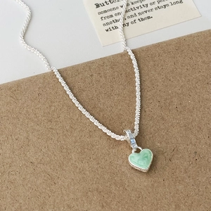 Détail du collier en argent avec pendentif coeur marbré vert clair sur une carte