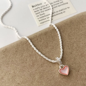 Détail d'un pendentif cœur en émail orange avec nacre sur une chaîne en argent torsadé