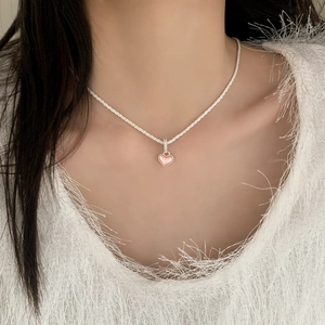 Détail du collier avec pendentif cœur rose et chaîne en argent scintillante sur un mannequin