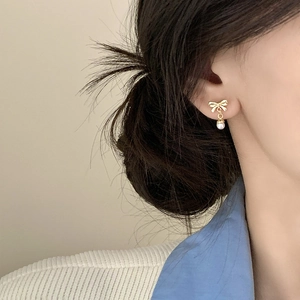 Elegant gold bow earrings with pearl pendant shown on model for a stylish daily look