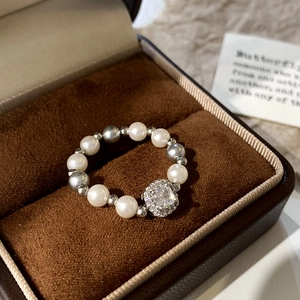 Macro shot of pearl beaded ring with square diamond center in a velvet jewelry box