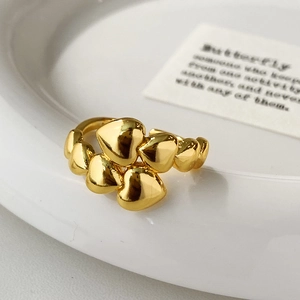 Macro shot of gold heart ring with polished 3D heart shapes on a ceramic plate