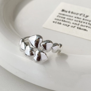 Detailed view of silver heart rings with a polished mirror finish on a white plate