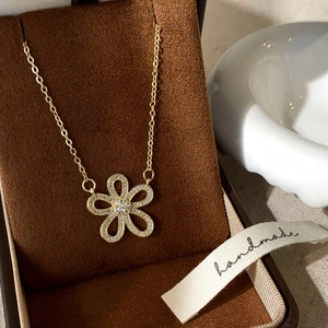 Close-up of a gold flower necklace with cubic zirconia petals in a luxury jewelry box